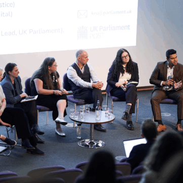 An image of eight people sitting at the front of a lecture hall as part of a panel discussion.