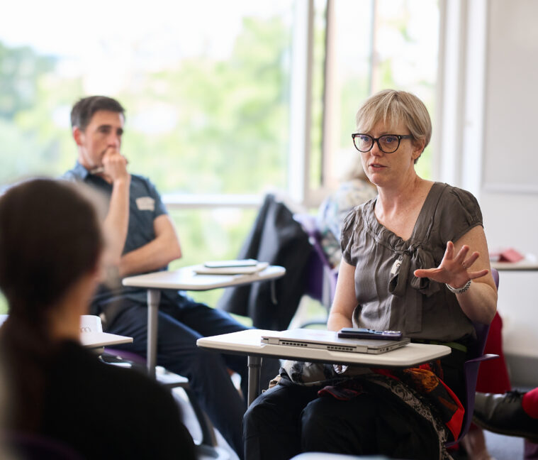 Photo of people sitting at desks in conversation.