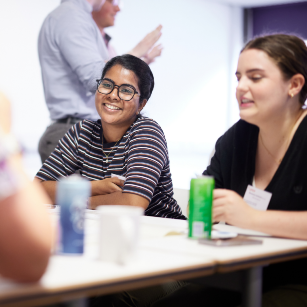 Person smiling while sat at a table discussion