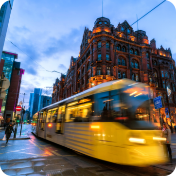 Decorative image of a tram travelling through Manchester City Centre