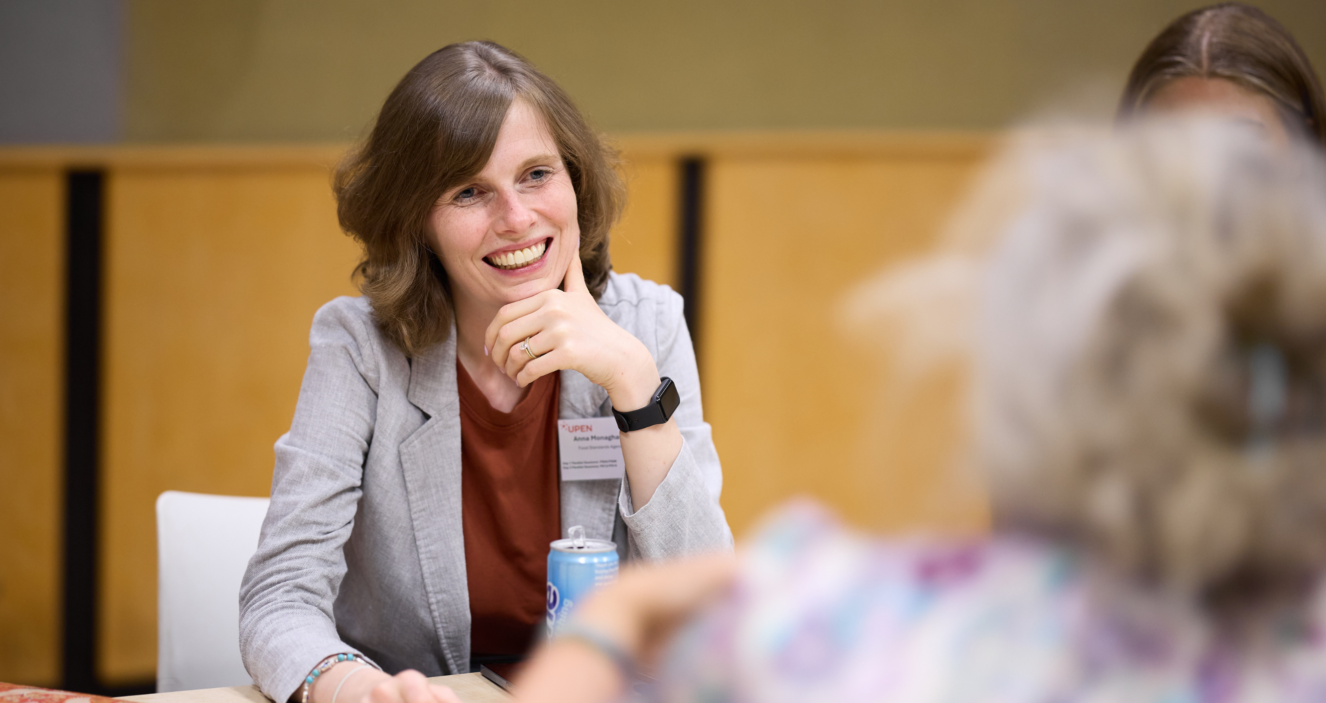 A person sat smiling and listening at a table.