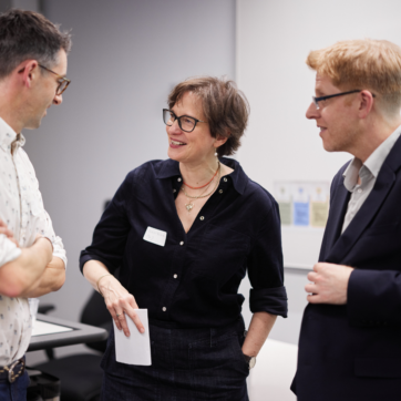 Three people stood talking at an event.